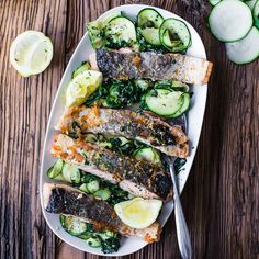 grilled fish with zucchini and cucumbers on a white platter