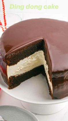 a chocolate cake on a white plate with one slice cut out and ready to be eaten