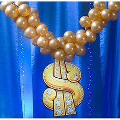 some gold balloons are hanging in front of a blue curtain with the letter s on it