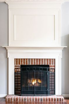 a fire place in the middle of a living room with wood floors and white walls