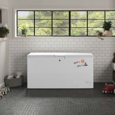 a white chest freezer sitting on top of a kitchen floor next to a window