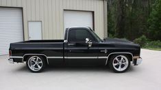 a black truck parked in front of a garage