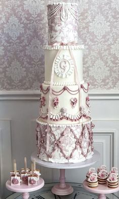 a three tiered cake on a table with cupcakes