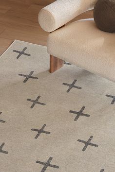 a beige rug with crosses on it and a chair in the corner next to it