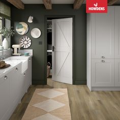 a kitchen with white cabinets and green walls, an area rug in front of the door