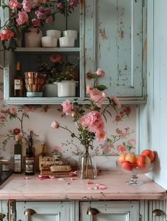 pink flowers in vases on top of a kitchen counter next to an old cabinet