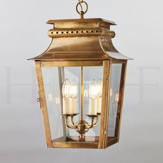 a brass hanging light fixture with three candles