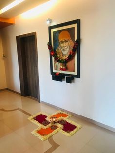 a painting hanging on the wall next to a decorated floor with flowers and garlands