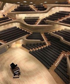 an empty auditorium with rows of seats and a piano on the floor in front of it