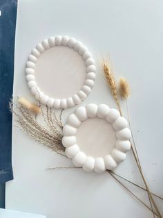 two white bracelets sitting on top of a table next to some dried grass and wheat