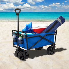 a blue wagon filled with items on top of a sandy beach