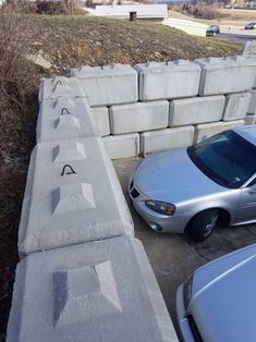 a car parked in front of a concrete block wall with writing on it and two cars parked next to it