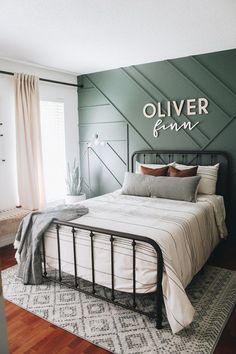 a bedroom with a metal bed frame and green accent wall behind it that says oliver finnn