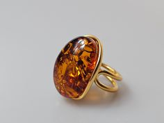 Amber ring. Brown Orange Baltic Amber gemstone ring. Certificated gold plalted Sterling silver 925 with stamps - hallmarks. Big nice stunning ring. Adjustable size. Very big and stunning amber gemstone ring.  weight 11 gr GOLD plated sterling silver 925 ring.  Stone size-  2,7x2  cm This item was made of natural Baltic Amber. All the amber used in my jewelry is collected in my home country Lithuania.  I sell only genuine,  real, not pressed, authentic, natural Baltic Amber. Item may have natural Elegant Amber Oval Rings, Elegant Amber Crystal Ring, Elegant Oval Amber Rings, Gold Crystal Ring With Polished Finish For Formal Occasions, Elegant Amber Cabochon Ring, Formal Amber Rings In Fine Jewelry Style, Amber Rings For Formal Occasions, Fine Jewelry, Amber Rings For Formal Occasions In Fine Jewelry Style, Formal Amber Open Ring Jewelry