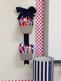 the wall is decorated with polka dot paper and two baskets filled with pens, pencils and markers