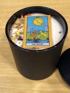 a candle with a tarot card in it sitting on a table next to a black container