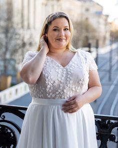 a woman in a white dress is posing for the camera with her hand on her head