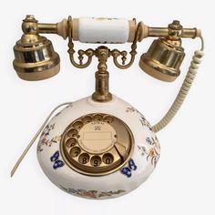 an old - fashioned phone is decorated with flowers and gold trimmings, as well as two bells