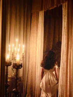 a woman standing in front of curtains with candles