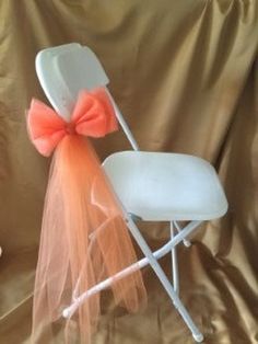 a white folding chair with an orange bow