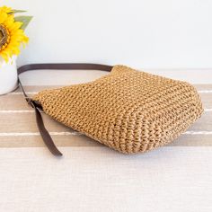 a straw bag sitting on top of a table next to a sunflower