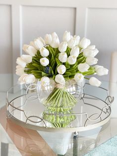 a vase with white flowers sitting on top of a glass table