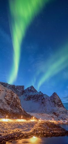 the northern lights shine brightly in the sky above snow covered mountains