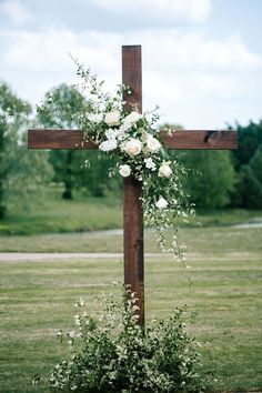 a cross with flowers on it in the grass