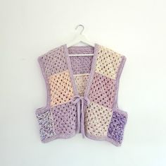 a crocheted vest hanging on a white wall