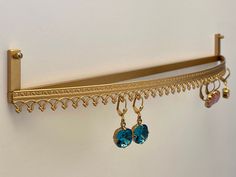 a pair of earrings hanging from a gold shelf