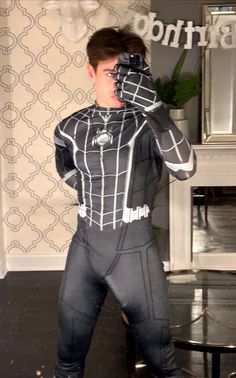 a young man dressed as spider - man is holding his hands up to his face