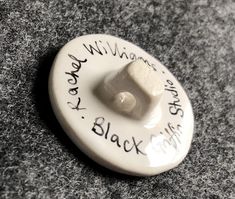 a white ceramic button with writing on it