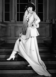 an old fashion photo of a woman in a long dress and hat standing on stairs