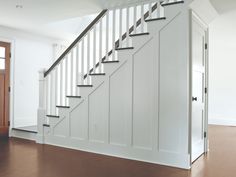 an empty room with a stair case next to a wooden door and brown flooring