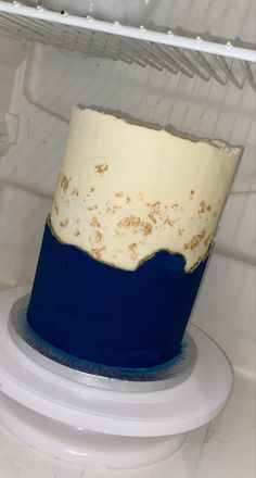 a blue and white cake sitting on top of a shelf in a refrigerator freezer