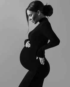 a pregnant woman poses for a black and white photo with her hands on her hips