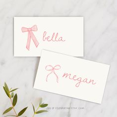 two personalized place cards with bows on them, one is pink and the other is white