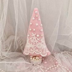 a small pink christmas tree with pearls on it's head and lace around the base