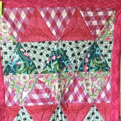 a quilted wall hanging with pink and green designs