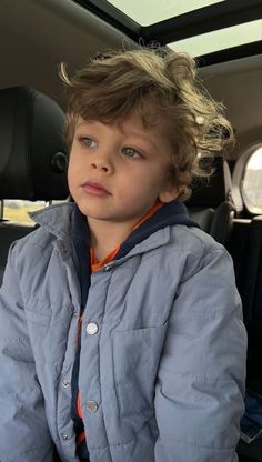 a young boy sitting in the back seat of a car with his head turned to the side