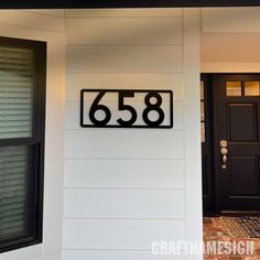 a house number sign in front of a black door