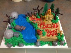 a birthday cake is decorated with animals and trees