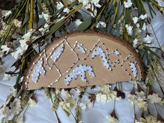 a wooden sign sitting on top of a table covered in flowers and branches with snowflakes