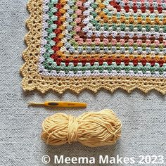 a crochet afghan with yarn next to it and a ball of knitting needles