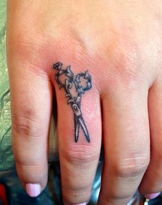 a woman's hand with a small tattoo on the middle finger and an arrow in the middle