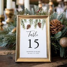 a table number sign with pine cones and greenery