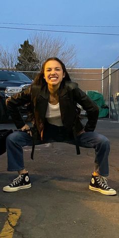 a woman sitting on top of a skateboard in the middle of a parking lot