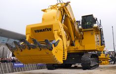 a large yellow machine sitting on top of a dirt field