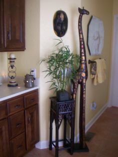 a tall giraffe statue sitting next to a plant on top of a table