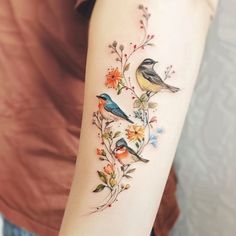 a woman's arm with birds and flowers on the left side of her arm